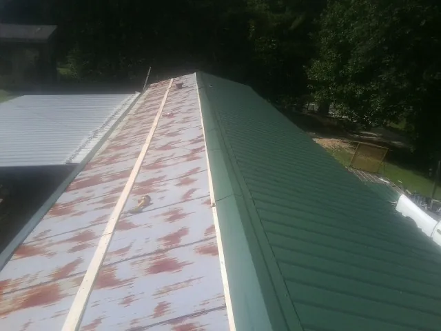 Old rusted panels beside newly installed green metal roofing — Wind Damage Roof Repair by Roofing Brothers in Klickitat