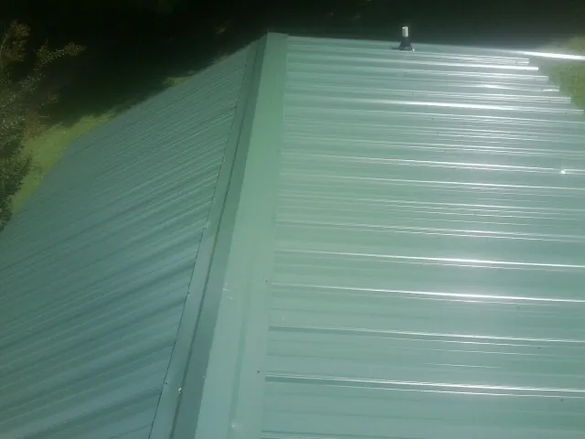 New green metal panels meeting at the ridge of a roof — Flat Roof Repair work by our crew in Klickitat