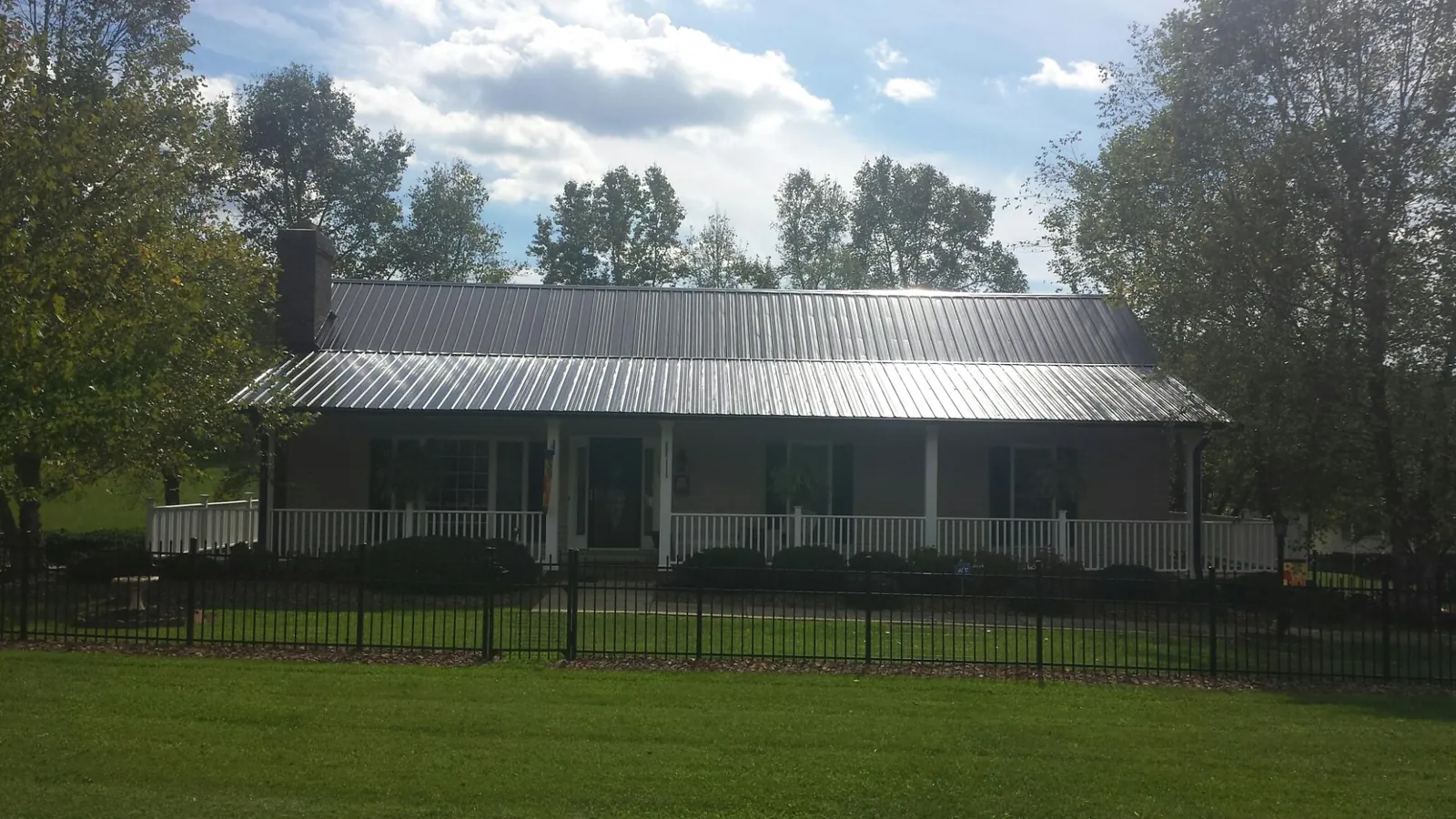 Gray metal roof on a brick ranch with a full width front porch — Gutter Guard Installation work by our crew in Klickitat