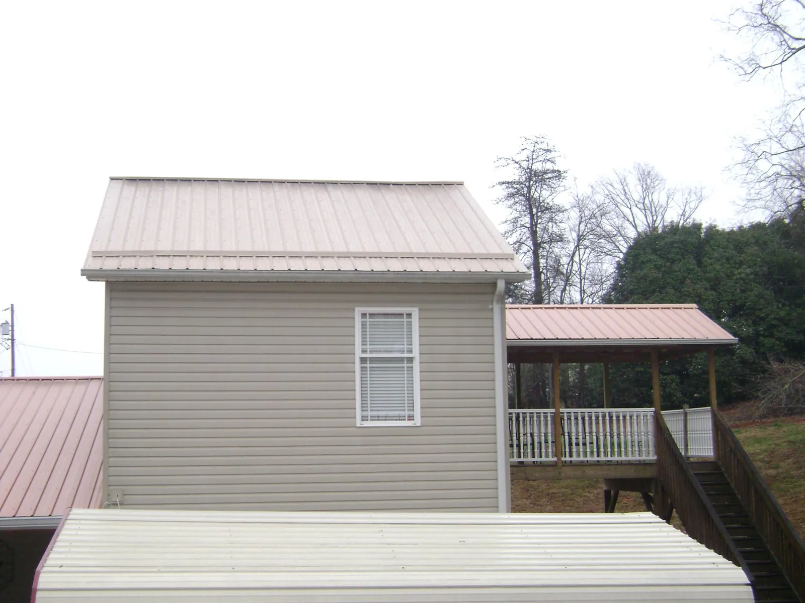 Tan metal roofs on a two story addition and attached porch, from a Roof Replacement job in Klickitat
