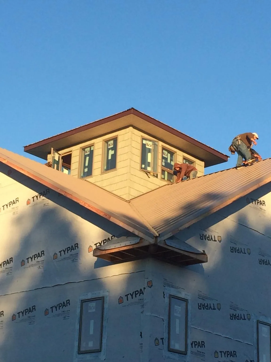 Roofers working around a rooftop cupola on a new metal roof at sunset — Roof Waterproofing in Klickitat by Roofing Brothers